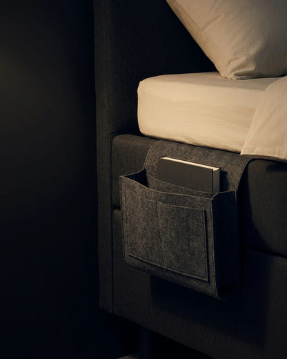 Grey Felt Bedside Caddy shown hanging beside a bed for scale