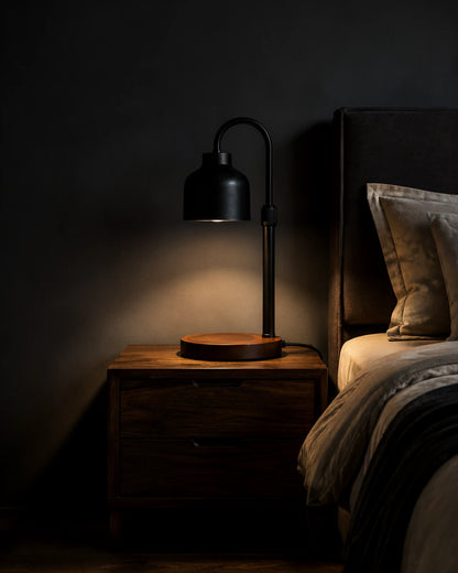 Black Nordic candle warmer lamp on a dark walnut nightstand beside a bed