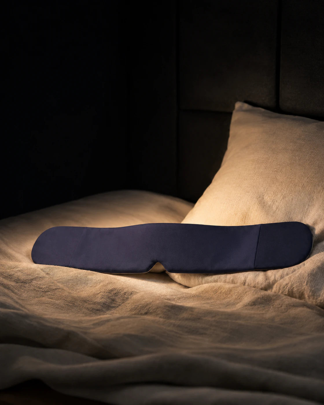 Blue weighted sleep mask on a dark bedside surface