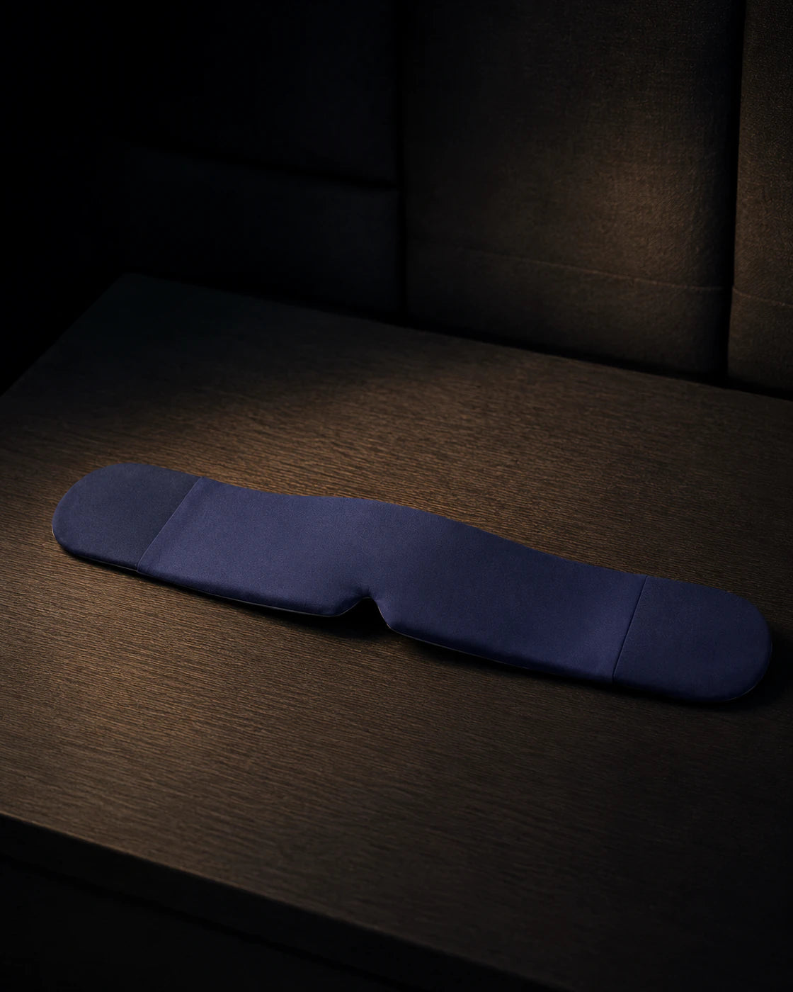 Blue weighted sleep mask isolated against a dark background
